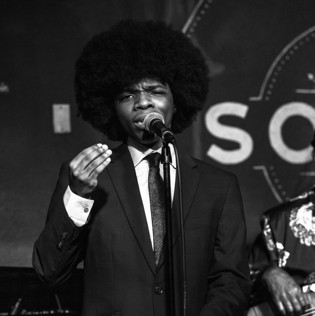 nathanael-barlow-lead-image Nathanael Barlow sings into a microphone onstage