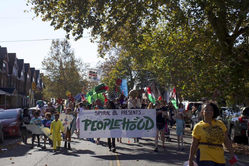 People walk together holding a banner sign that reads Peoplehood