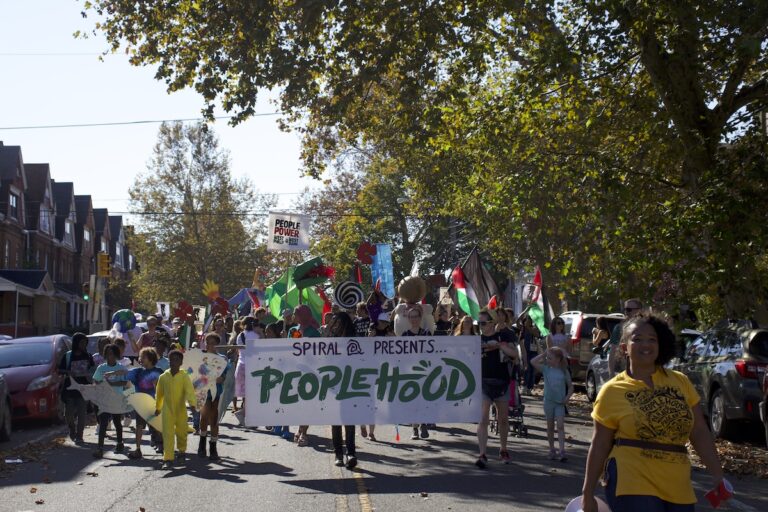 People walk together holding a banner sign that reads Peoplehood