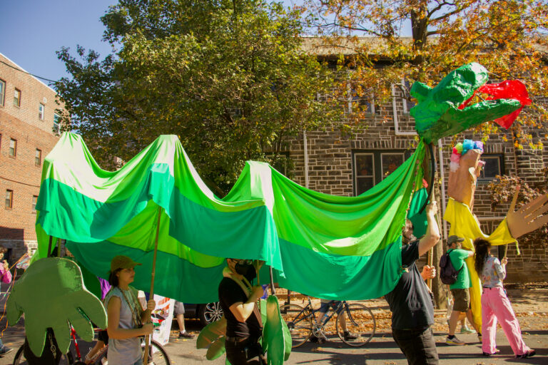 A giant puppet propelled by different people walks down the street