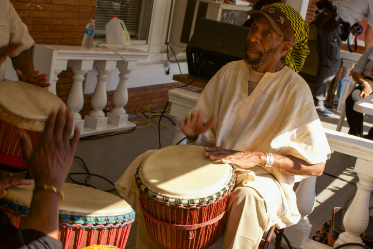 People playing drums on a porch.