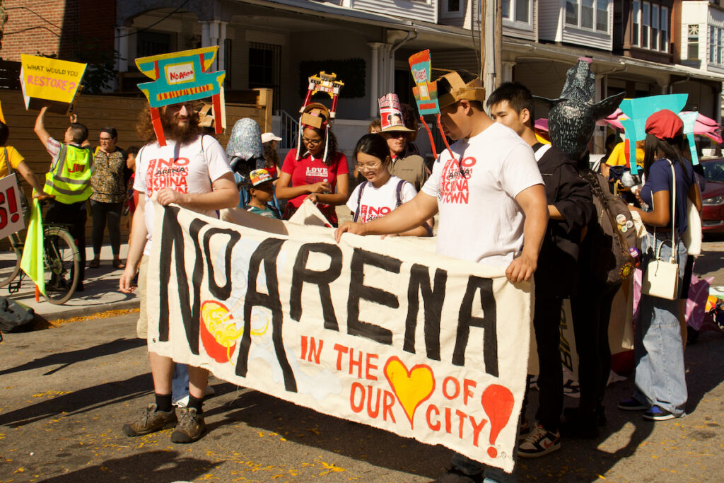 People hold a sign that reads "No Arena in the heart of our city"