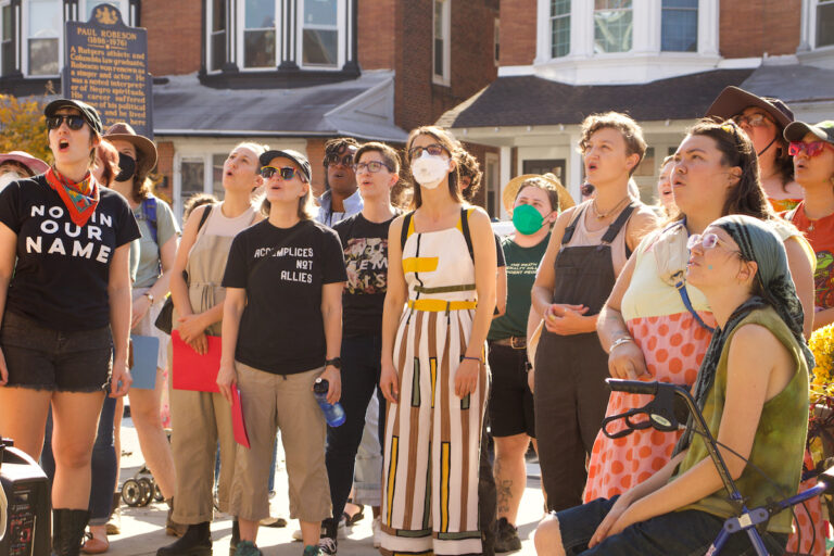 People standing together on the street sing together.