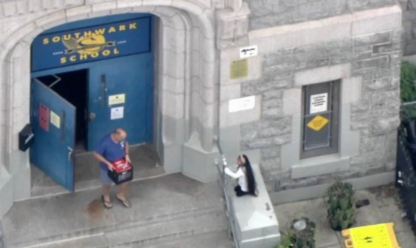 southwark-elem-asbestos A person leaving out of the front door of Southwark Elementary with a box of possessions in hand.