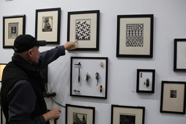 Art collector and dealer Rock Walker discusses the M.C. Escher pieces on display at the Front St. Gallery in Fishtown on Nov. 12, 2023. (Cory Sharber/WHYY)