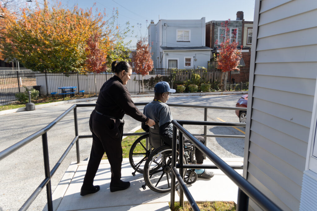 Vanessa Morbeck pushes Leon Brantley in his wheelchair down a ramp.