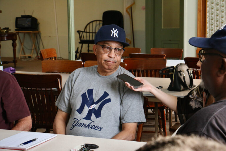 Bill Corbin listens while seated at a table with other people.