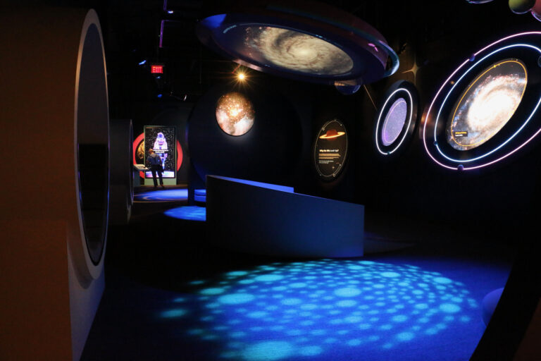 Images of planets and solar systems are stationed around the room.