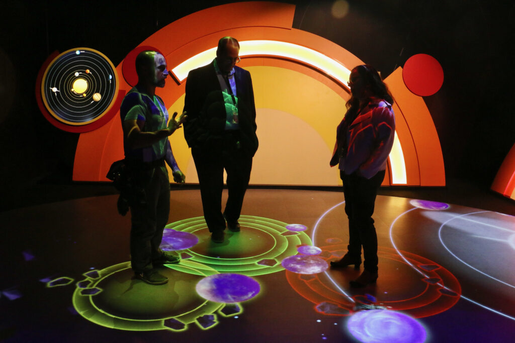 Planets, asteroids and comets swirl around the feet of visitors who become sources of gravitiy when they step onto the floor.