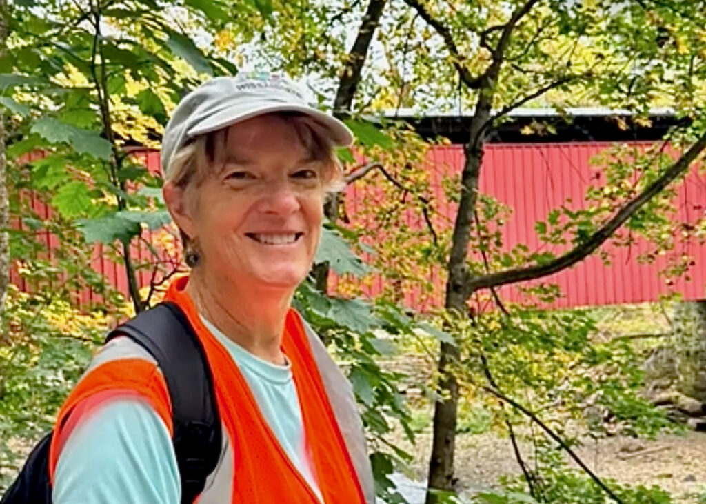 Jean McWilliams smiles while posing for a photo. Trees are visible behind her.