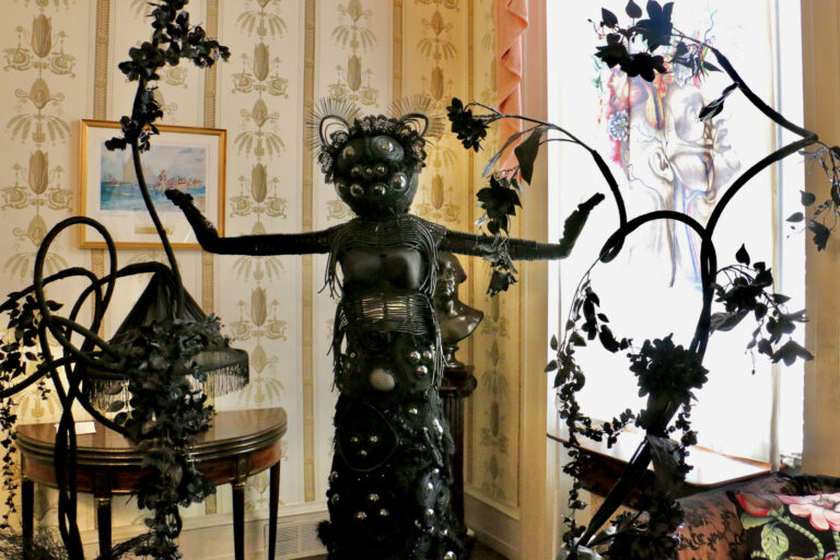 A sculpture of a feminine figure with the eyes of a spider