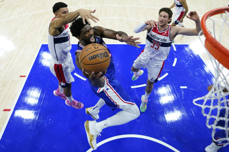 Philadelphia 76ers' Joel Embiid (center) goes up for a shot against Washington Wizards' Johnny Davis, left, and Mike Muscala during the second half of an NBA basketball game, Monday, Nov. 6, 2023, in Philadelphia. (AP Photo/Matt Slocum)