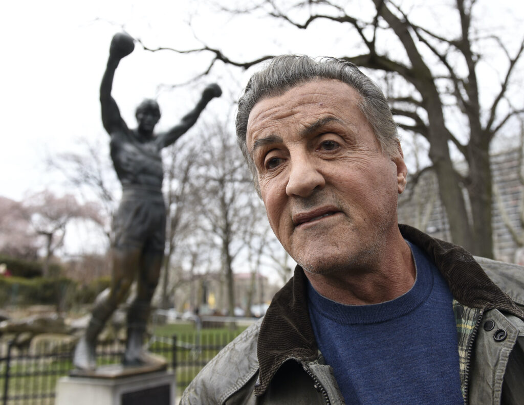 Sylvester Stallone in front of his statue