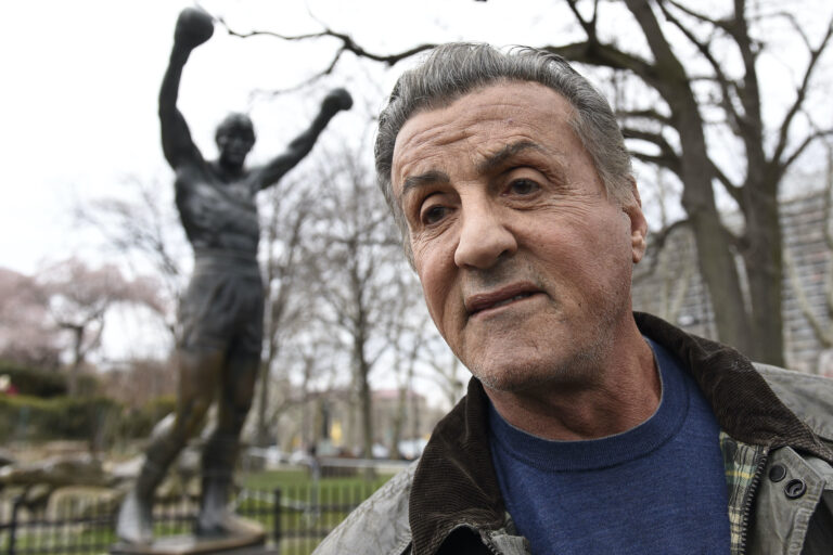 Sylvester Stallone in front of his statue