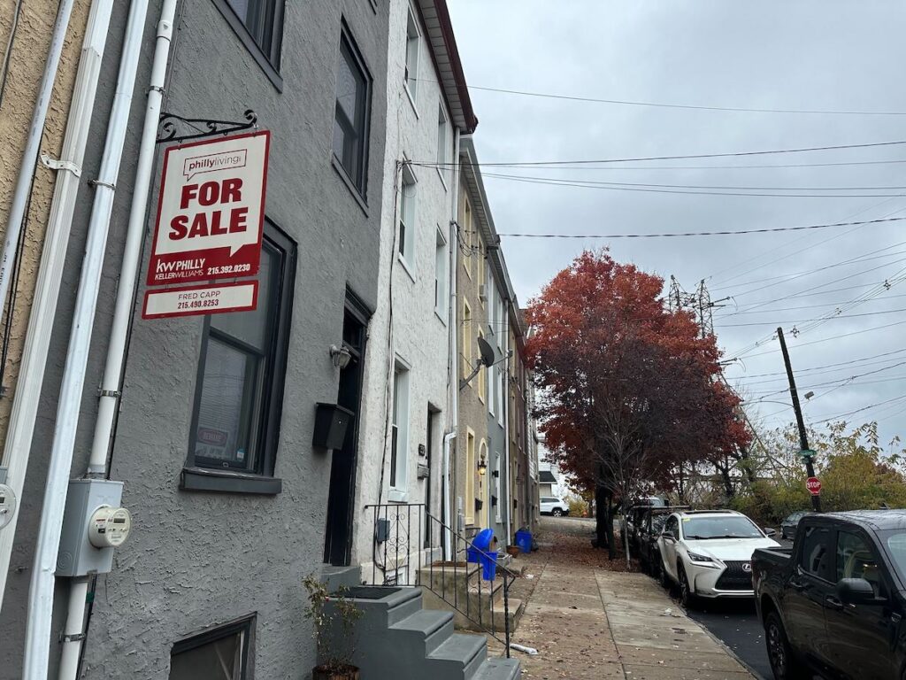 Housing1 A for sale sign hangs outside of a rowhome