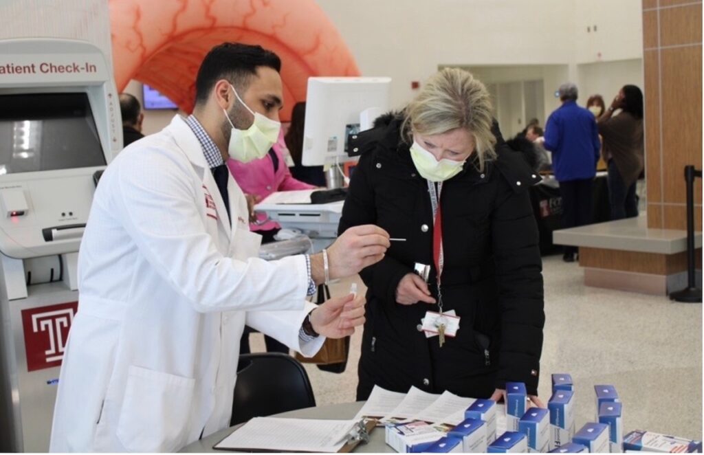 Dr. Rishabh Khatri (left), chief resident in the department of internal medicine at Temple University Hospital, shows someone how a FIT screening kit works.