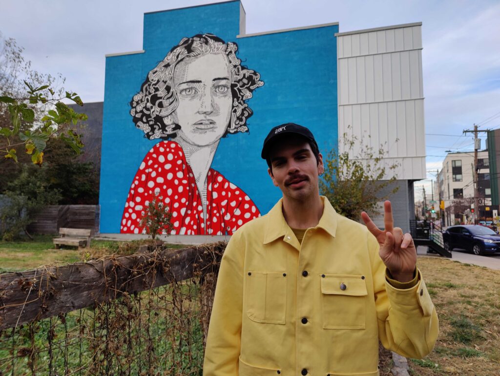 conrad-benner-2023-11-20 Conrad Benner stands in front of a mural in Fishtown
