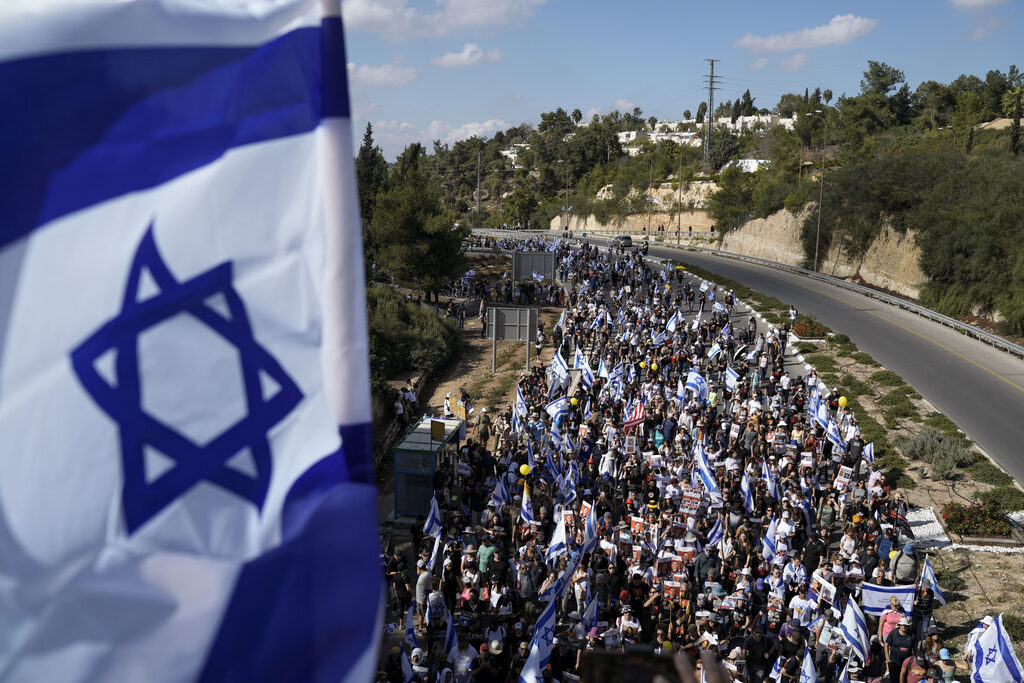 Israel Palestinians A flag of Israel is visible, and stretching into the distance is a crowd of people marching