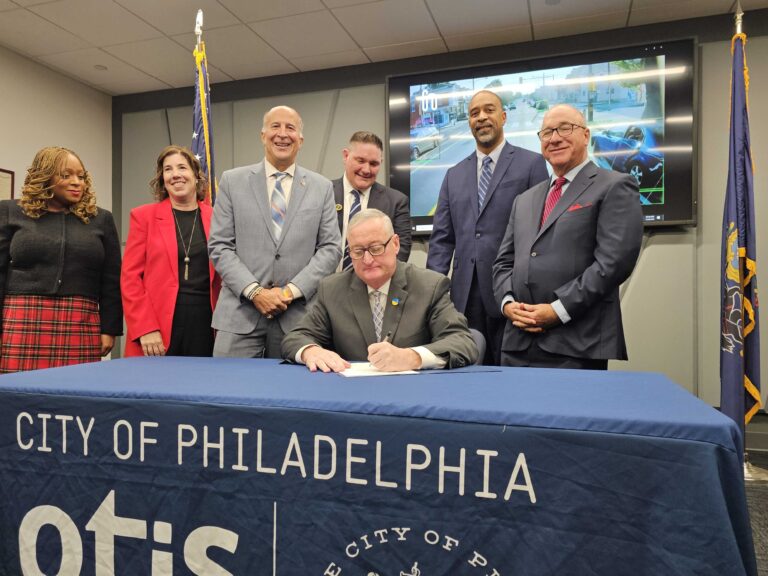 Mayor Kenney sigining a bill with other officials surrounding him.