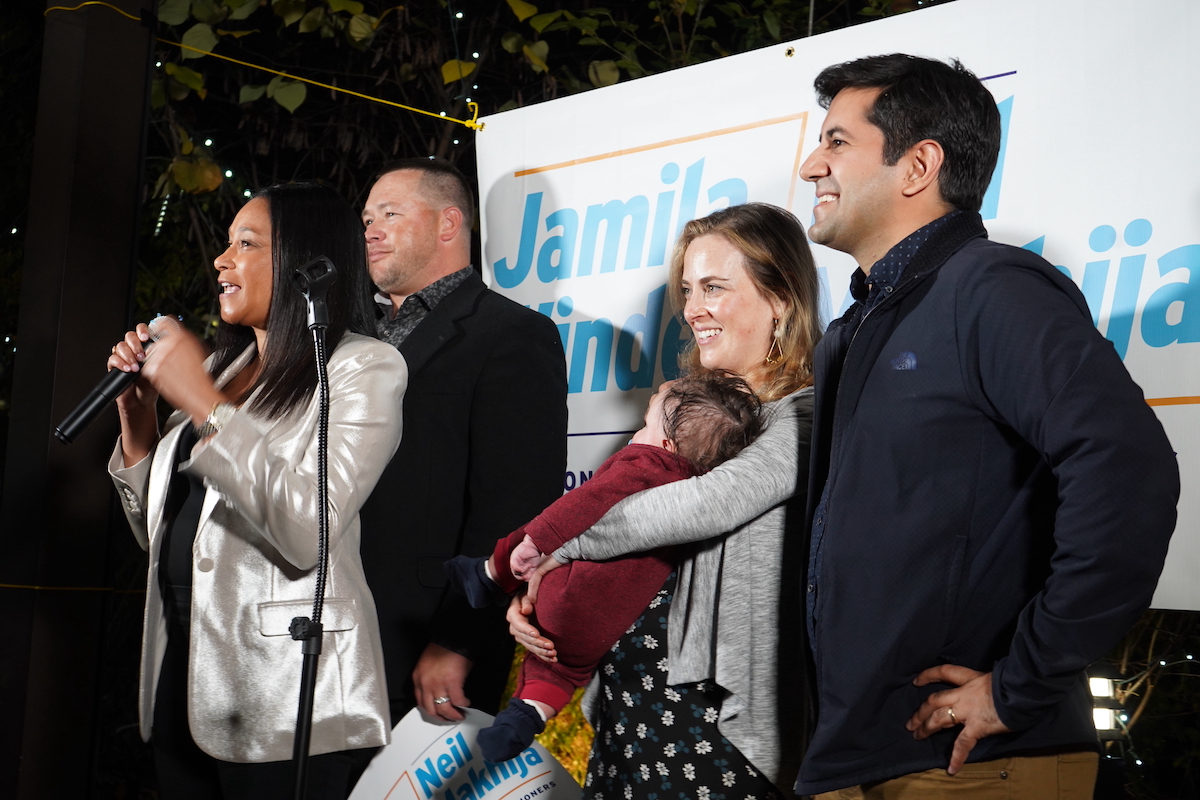 Montgomery County Democrats Jamila Winder and Neil Makhija celebrate next to the podium with their families.