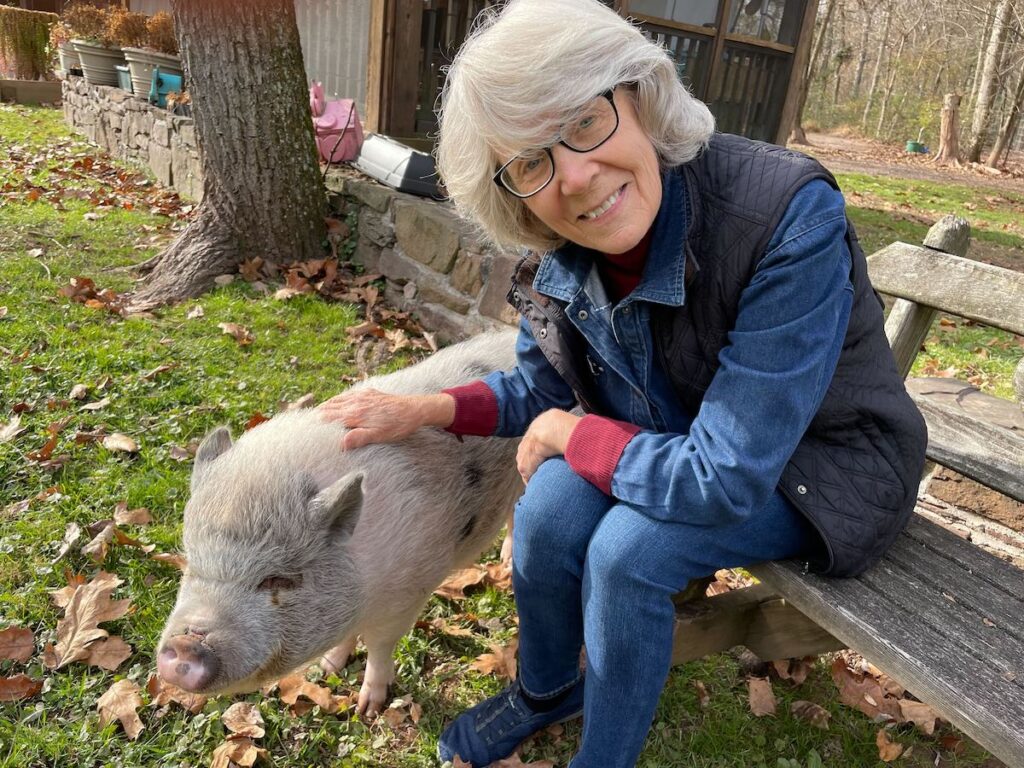 pig-placement-network-2 Susan Armstrong-Magidson poses for a photo while seated on a bench next to pet pig Fiona