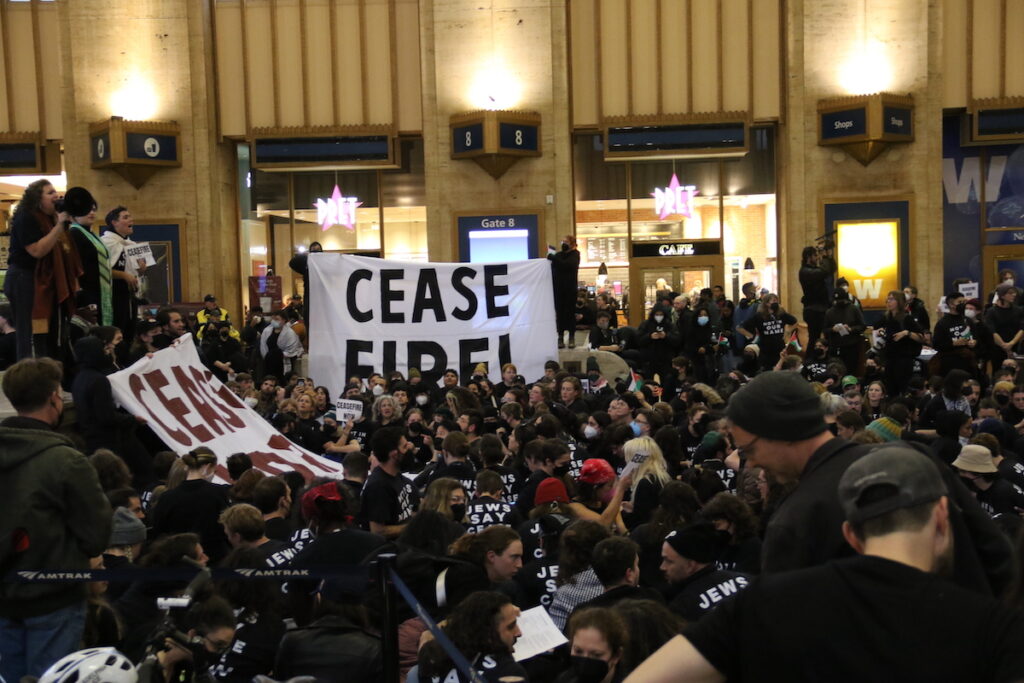 protest-30th-street-station-10 Hundreds of people gathered in Philadelphia 30th Street Station's main terminal hold a sign that reads Ceasefire!