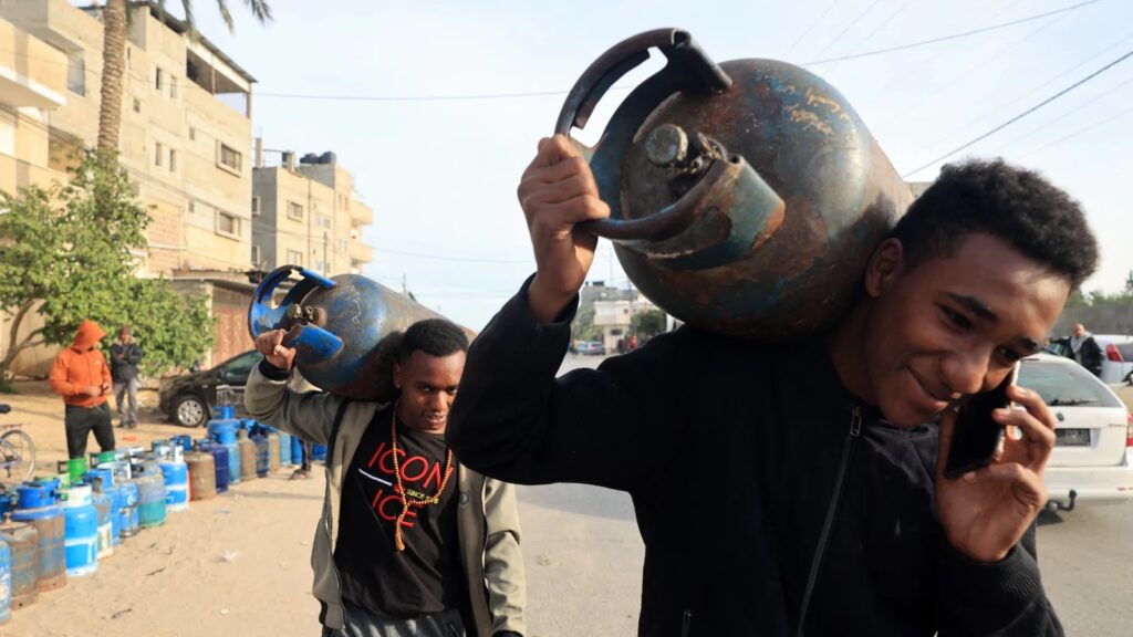 rafah-egypt-palestinian Men carry empty canisters to be filled with cooking gas from a tanker