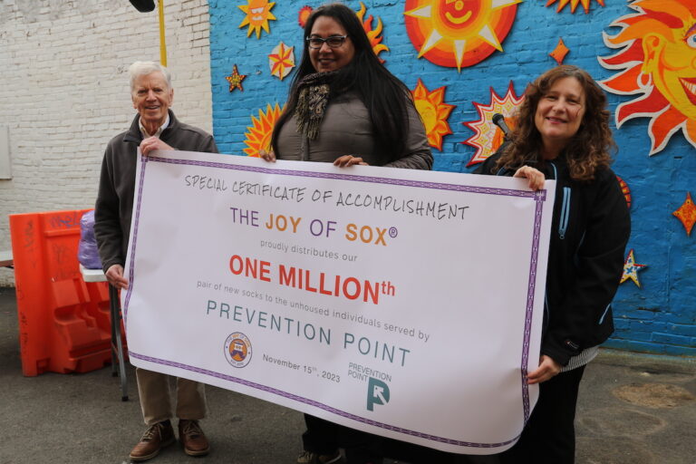 People hold up a sign that reads The Joy of Sox One millionth prevention point.