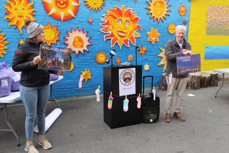 People hold up signs reading Philadelphia and Toronto