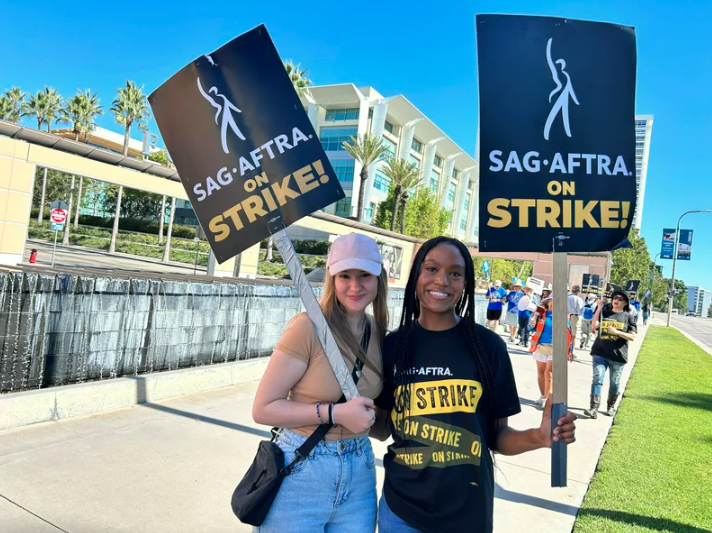 Allie Palm and Desiree Woolfolk stand outside Fox studios with SAG-AFTRA picket signs