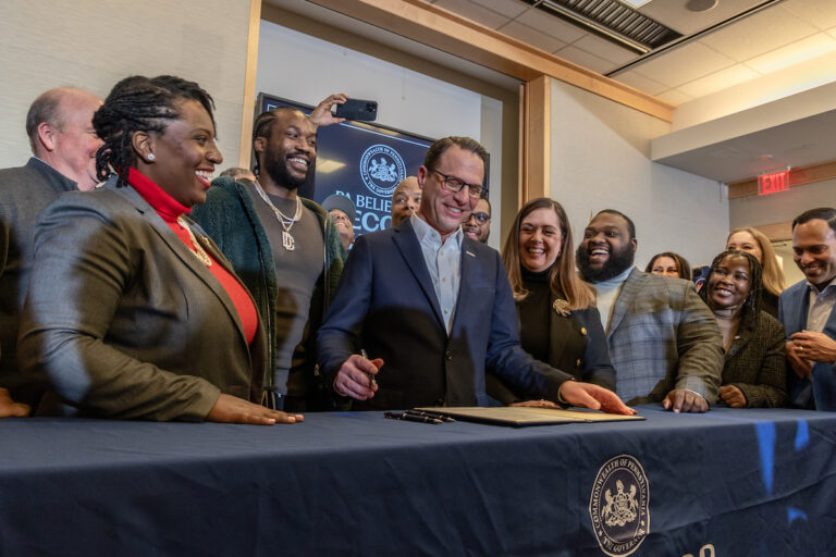 Pa. Governor Josh Shapiro smiles as he signs a bill surrounded by people