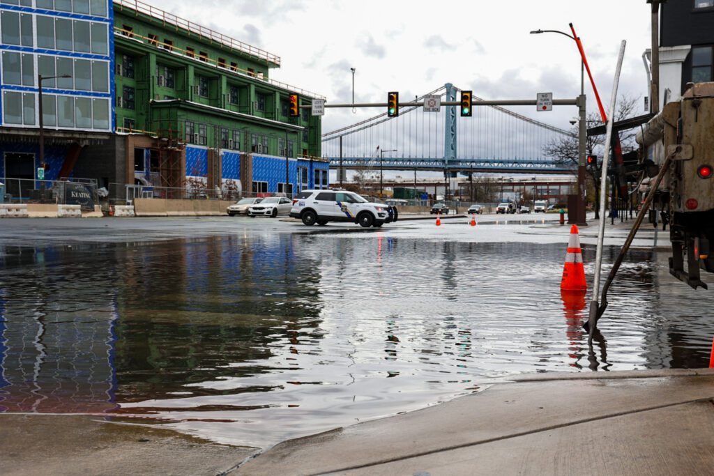 12 18 2023 kpaynter dekaware river flooding post storm-5 A flooded street in Philadelphia, with a bridge visible in the distance.