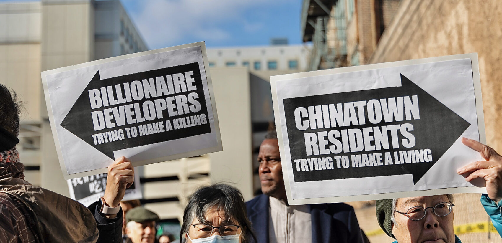 People holding up signs protesting the potential new arena for the Sixers in Chinatown.