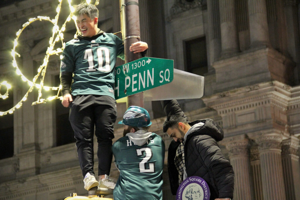 Eagles fans climb street light poles.