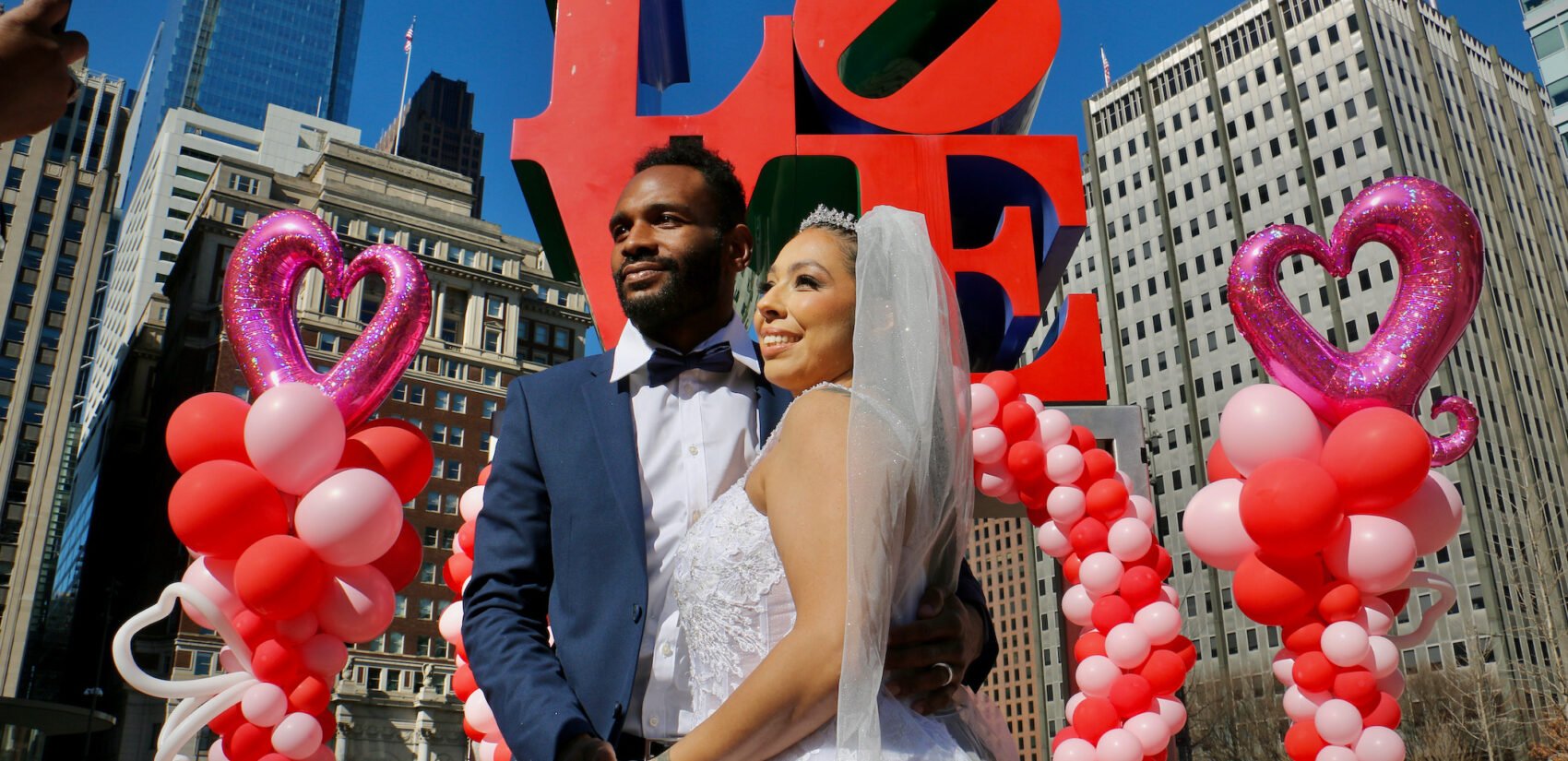 Bride and groom posing in front of the LOVE statue at LOVE Park
