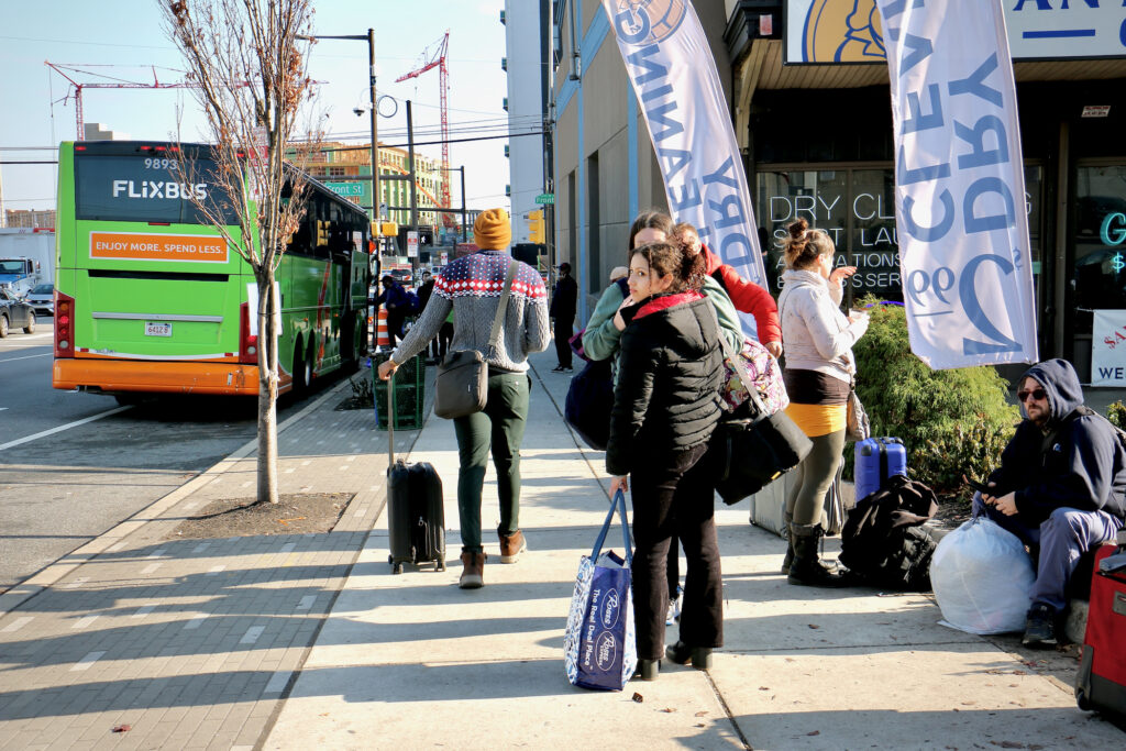 2023-12-08-e-lee-philadelphia-spring-garden-street-waiting-for-the-bus people waiting on the sidewalk for the bus.