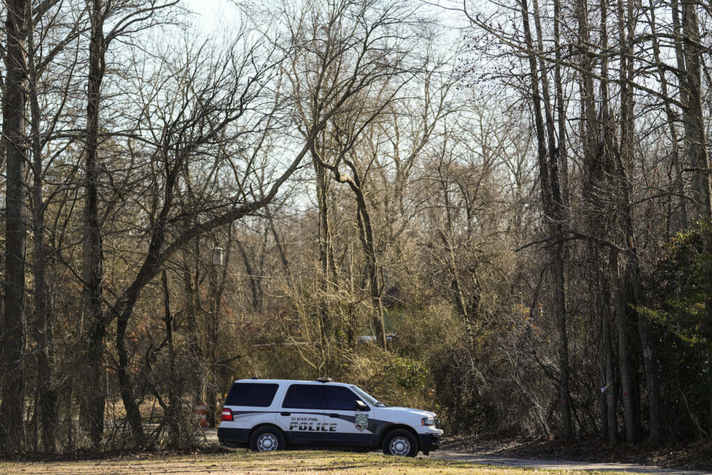 A police vehicle is parked on a road leading to the scene of a helicopter crash in Washington Township