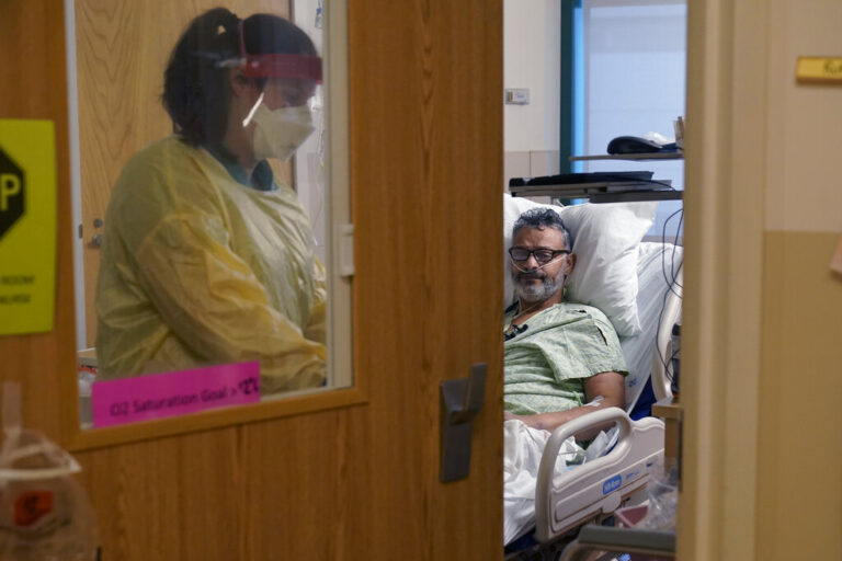 A nurse departs the room of a COVID-19 patient
