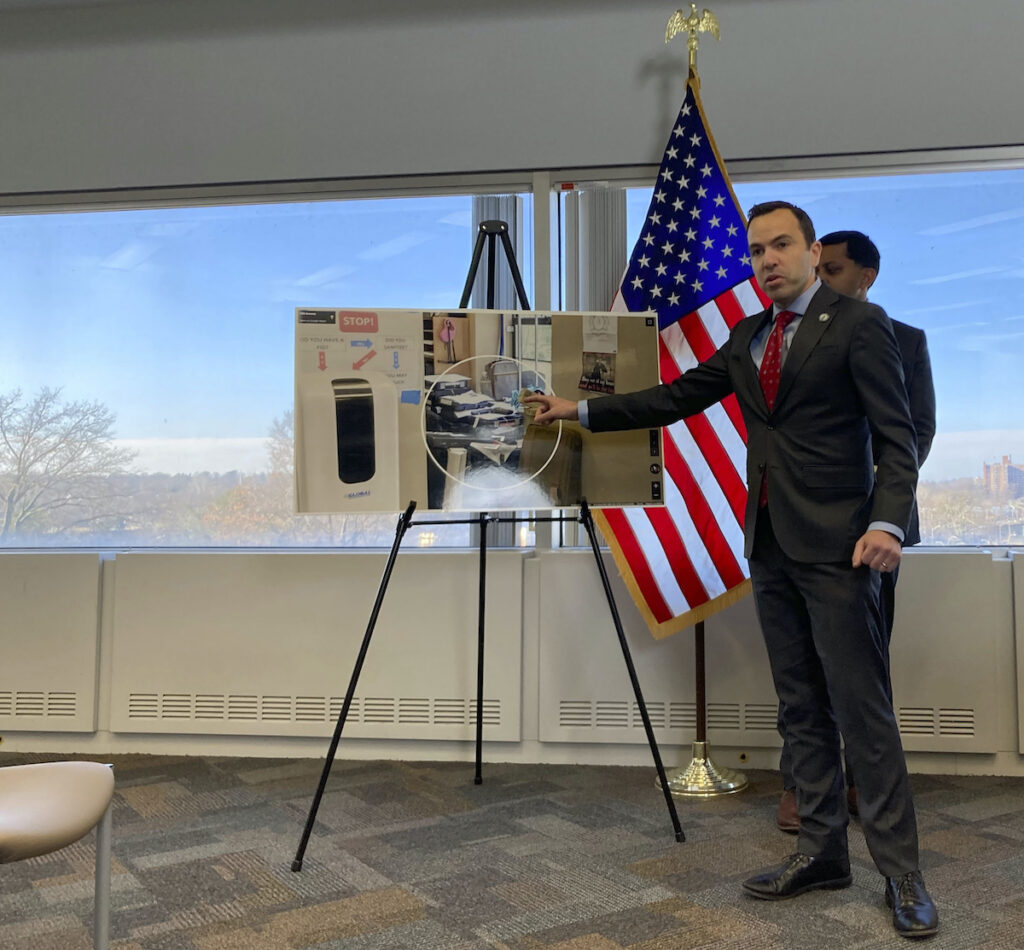 New Jersey Attorney General Matt Platkin points to a photo he says shows guns stored near a ground-floor window at a gun shop, contrary to state law, on Tuesday, Dec. 12, 2023, in Trenton, N.J. The shop was one of three gun dealers Platkin sued on Tuesday. The suits were the first brought by his office under a 2022 law aimed at holding gun dealers accountable by allowing the attorney general to sue under New Jersey's public nuisance laws. (AP Photo/Mike Catalini)