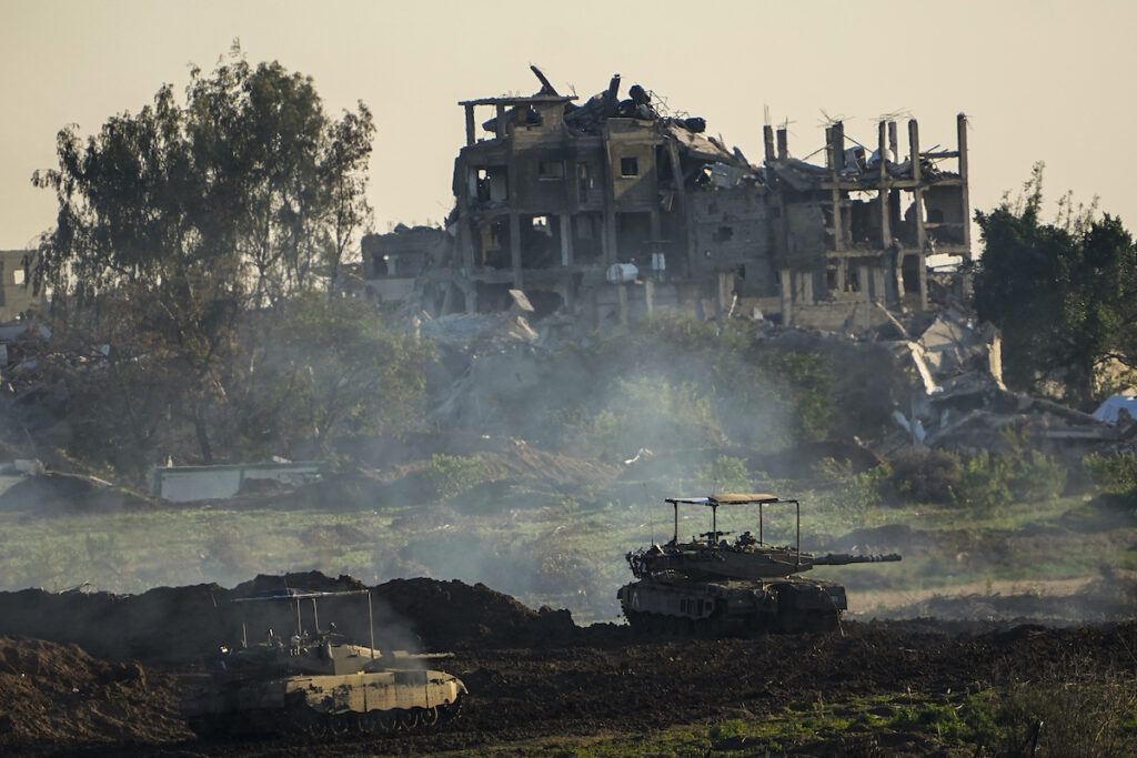 Israel Palestinians Israeli tanks are seen next to a destroyed building during a ground operation in the northern Gaza Strip, Friday, Dec. 15, 2023. The army is battling Palestinian militants across Gaza in the war ignited by Hamas' Oct. 7 attack on Israel. (AP Photo/Ariel Schalit)