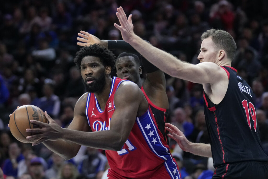 Raptors 76ers Basketball Philadelphia 76ers' Joel Embiid (left) tries to get by Toronto Raptors' Dennis Schroder (center) and Jakob Poeltl during the first half of an NBA basketball game, Friday, Dec. 22, 2023, in Philadelphia