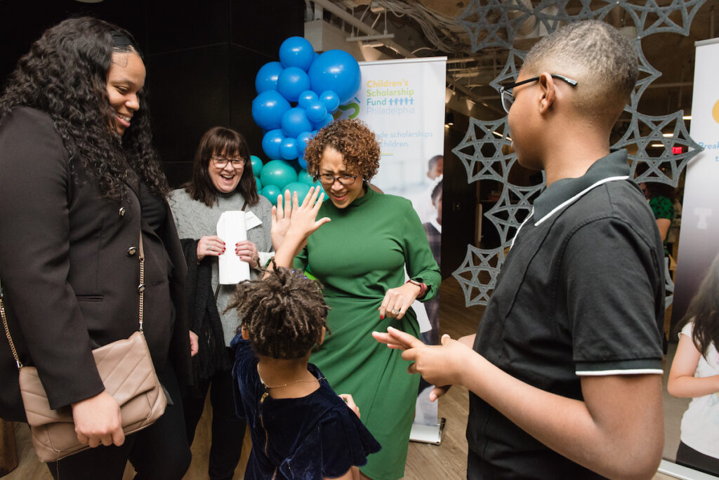 Children fund organizer Zora Battle high fives president and CEO of Children’s Scholarship Fund Philadelphia Keisha Jordan while her mother, Zecharia Artemus and her brother, Zaire Denson watch.