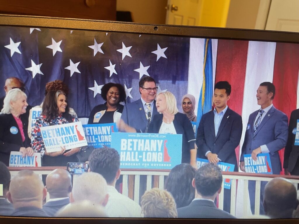 Bethany Hall-Long and husband Dana Long speak into a microphone at an event.