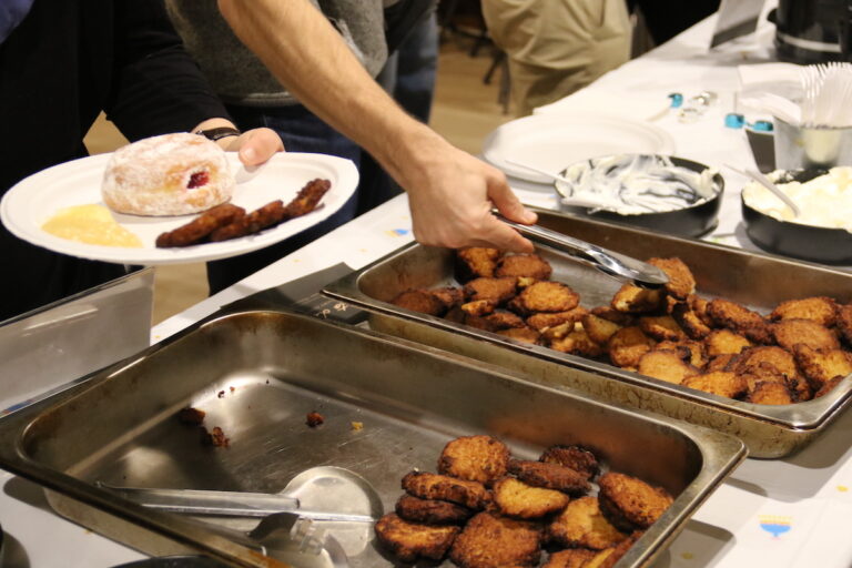 A person serves themselves latkes.