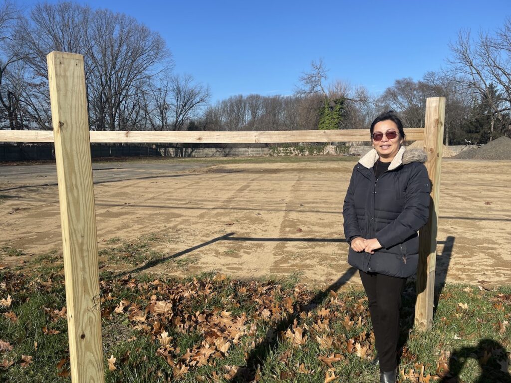 thao-le-property-cinnaminson Thao Le stands next to a fence and an open area that's her property.