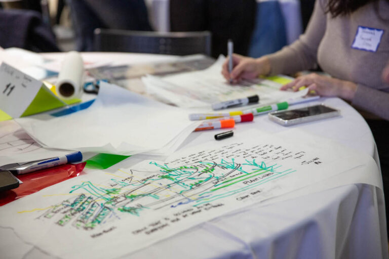 An upclose view of a design drawing and someone drawing in the background