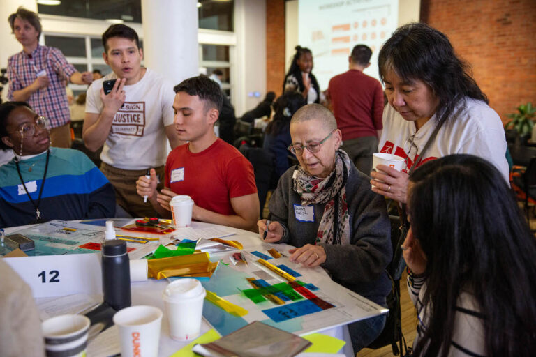 Debora Kodish, third from right, works with staff and community members at one of the community tables.