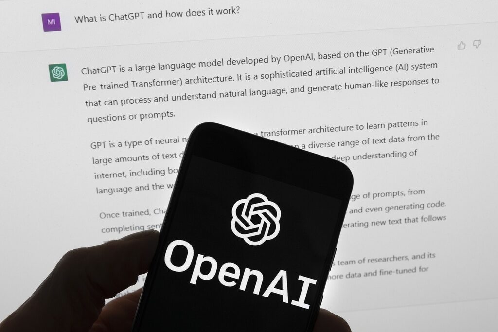 FILE - The OpenAI logo is seen on a mobile phone in front of a computer screen which displays output from ChatGPT, March 21, 2023, in Boston. Campaigns will be required to clearly state that political advertisements airing in Michigan were created with the use of artificial intelligence under legislation expected to be signed in the coming days by the Democratic Gov. Gretchen Whitmer. The use of AI-generated deepfakes within 90 days of an election will be prohibited without a disclosure identifying the media as manipulated. (AP Photo/Michael Dwyer, File)
