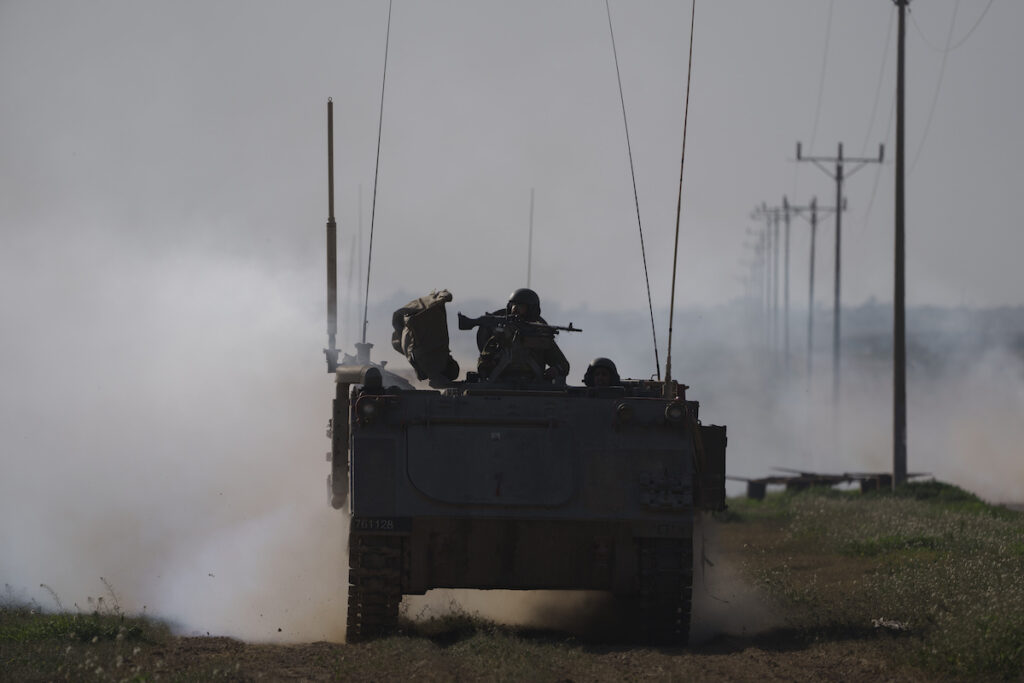 Israel Palestinians Israeli soldiers travel on an army armored personnel carrier (APC) near the Israeli-Gaza border as smoke rises to the sky in the Gaza Strip, seen from southern Israel, Sunday, Jan. 21, 2024. (AP Photo/Leo Correa)