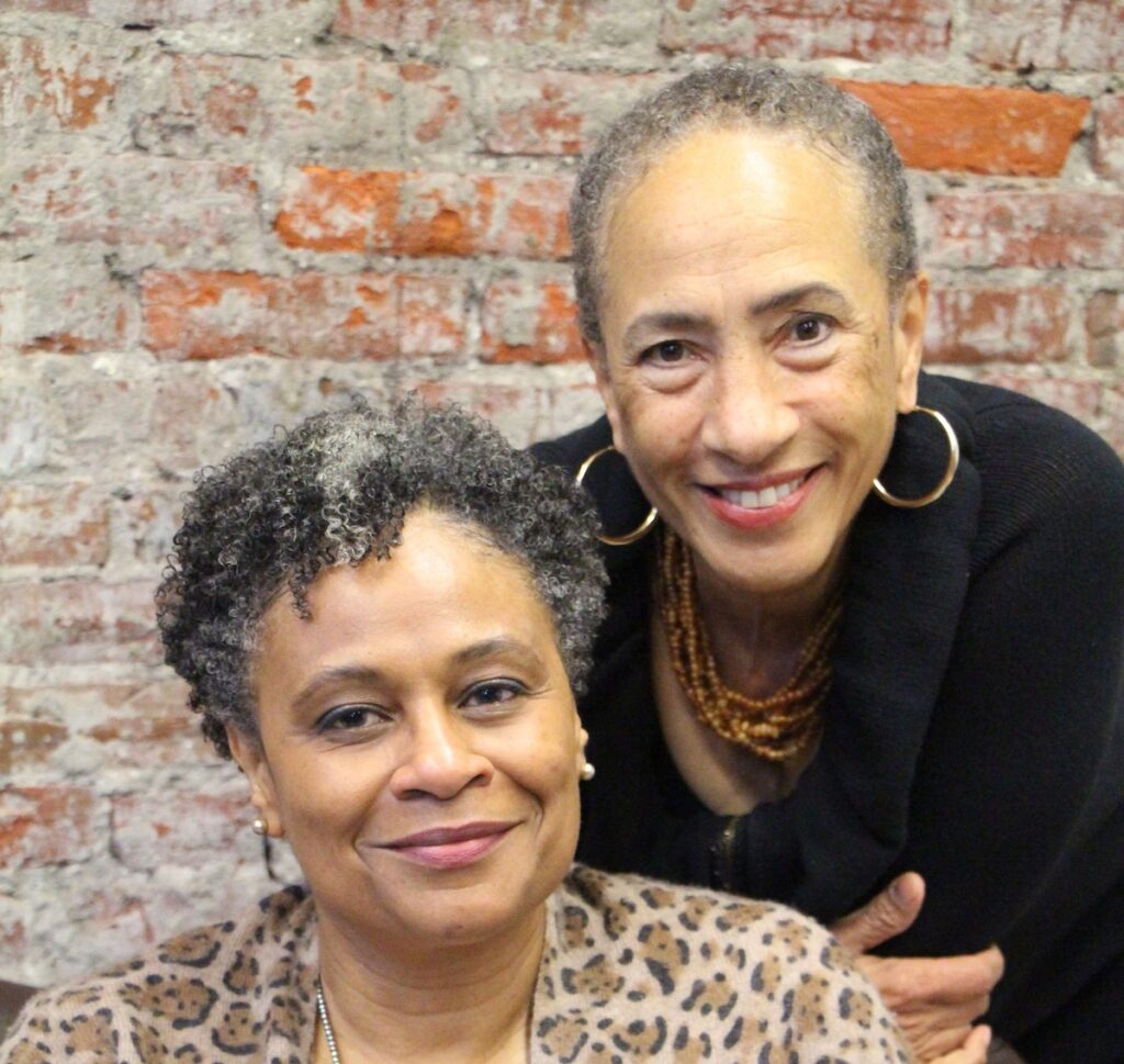 Lorene Cary, left, and Trazana Beverly, right, smile as they pose for a photo.